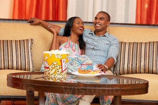 Couple laughing and Eating on Sofa