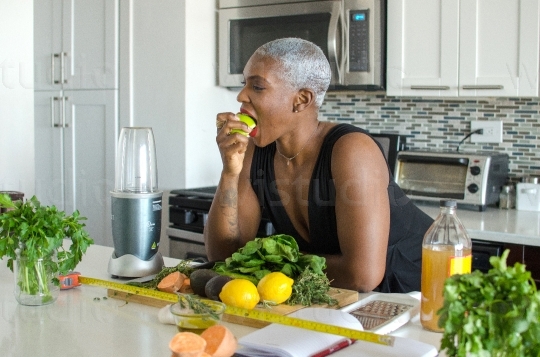 Woman Eating Fruit in Kitchen